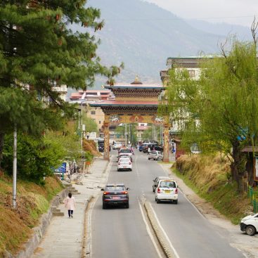 A street in Thimphu, Bhutan, with traffic and buildings on the hillside